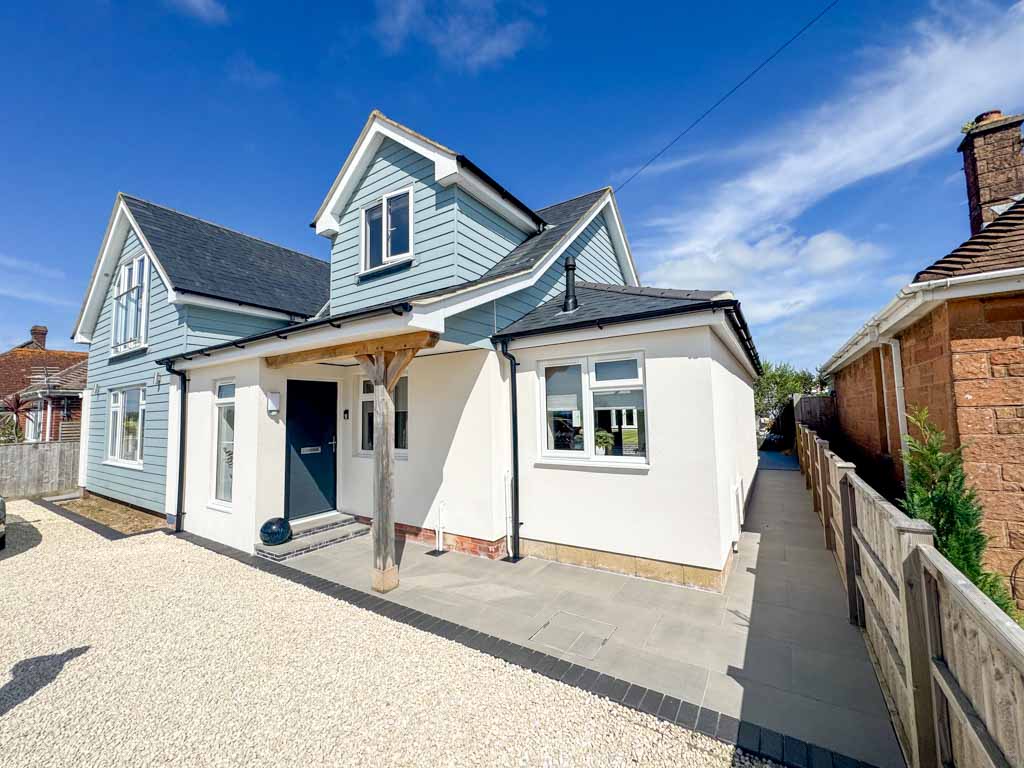Outdoor patio area with seating and a dining table, surrounded by a wooden fence and landscaped garden. The space is designed for relaxation and entertaining, with a tranquil and inviting atmosphere.